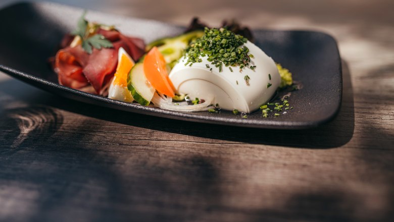 Hirschrohschinken mit Schafgupferl, © Niederösterreich Werbung/Daniela Führer Ein Teller mit Hirschrohschinken und Gemüse, garniert mit Kräutern.