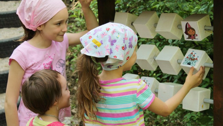 Märchenwald, © Tanja Schwartz Drei Kinder spielen an einem hölzernen Spielgerät im Freien.
