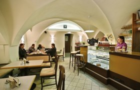 Café Colibri, © Susanne Karas Innenansicht eines gemütlichen Cafés mit gewölbter Decke, Tischen und einer Theke.