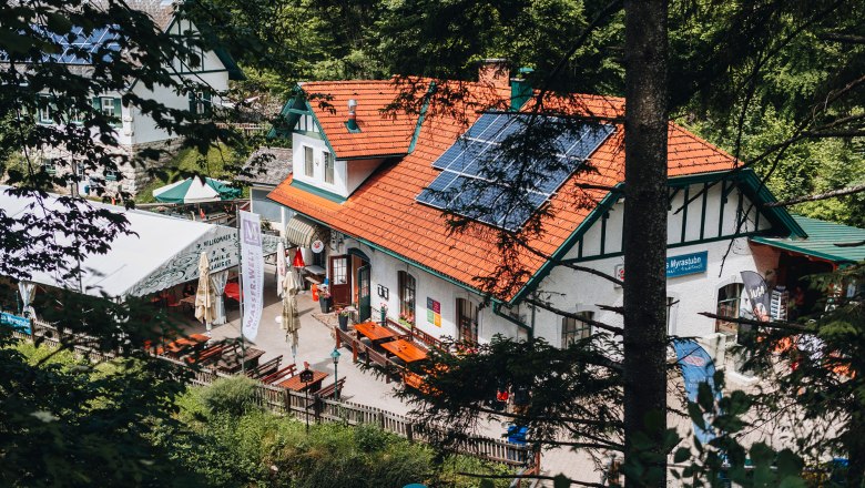 Beliebt bei Ausflugsgästen und Urlaubern, © Niederösterreich Werbung/David Schreiber Ein traditionelles Gasthaus mit Solarpanelen auf dem Dach, umgeben von Bäumen.