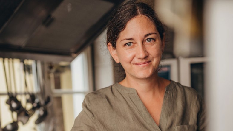 Gutbürgerliche Küche von Bernadette Fellner, © Niederösterreich Werbung/Daniela Führer Eine Frau in einer Küche, lächelnd, mit braunen Haaren und einem grünen Hemd.