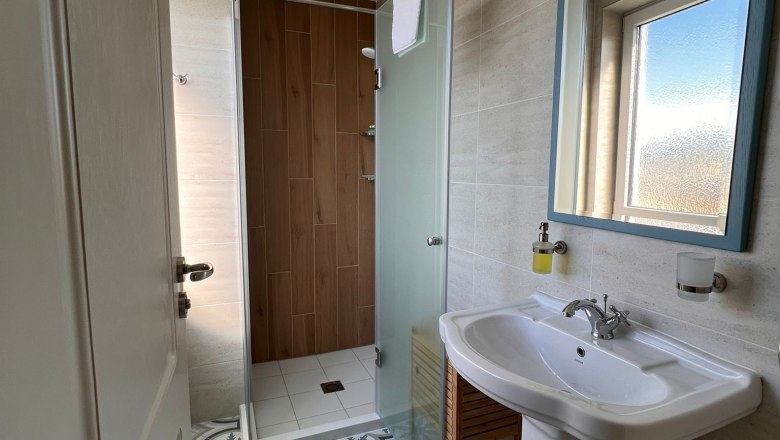 Badezimmer, © Mediterraneo Ybbs Modernes Badezimmer mit gemustertem Fliesenboden, Waschbecken, Spiegel und Dusche mit Glaswand.