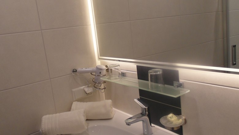 Badezimmer am Lugerhof, © Lugerhof Modernes Badezimmer mit Waschbecken, Spiegel und Handtüchern.