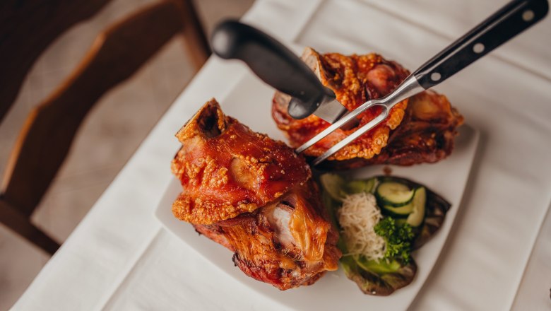 Ebenfalls beliebt: Die Schweinsstelzen, © Niederösterreich Werbung/Daniela Führer Zwei Schweinshaxen auf einem Teller mit Beilagen.