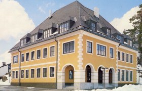 Gemeinde und Tourismusbüro Annaberg, © zVg Gemeinde Annaberg Gelbes Gebäude mit grauem Dach und vielen Fenstern, umgeben von Schnee.