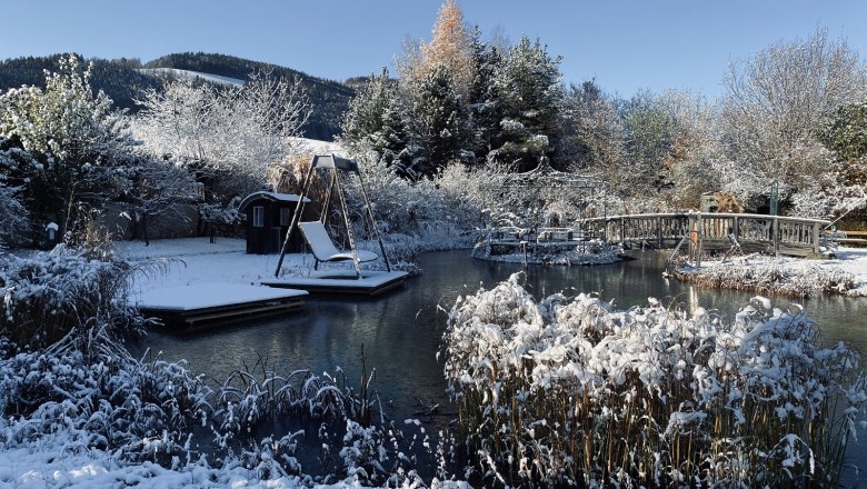 Paradiesgart' im Winter, © Hotel Molzbachhof, Peter Pichler Winterlicher Garten mit Teich, Brücke und Schaukel im Schnee.
