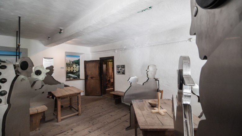 Erlebniswelt Mendlingtal, © Erlebniswelt Mendlingtal Innenraum mit Holzfußboden und Metallfiguren an Holztischen.