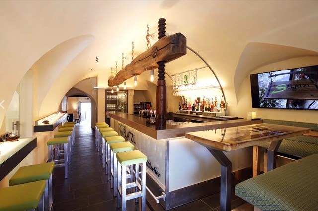 S Platzl Restaurant, © Schilowsky_NM_©redtenbacher Innenansicht eines modernen Restaurants mit Bar, grünen Hockern und gewölbter Decke.