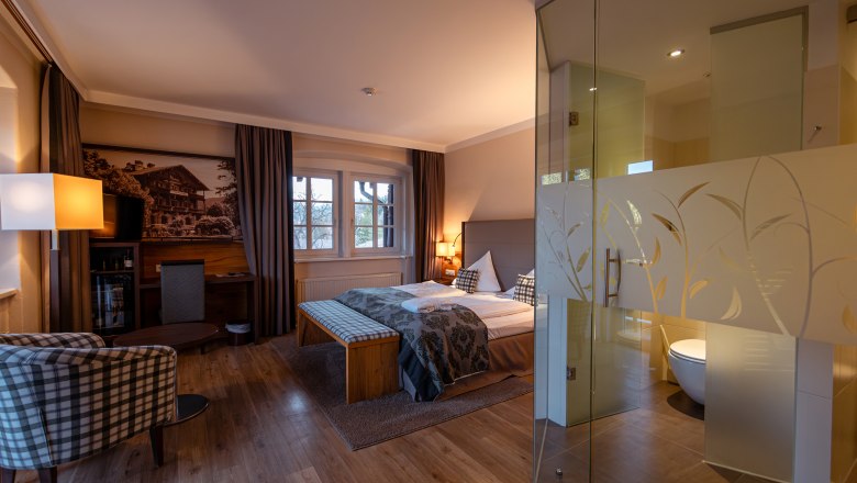 Hotel Schneeberghof, © Niederösterreich Werbung / Maximilian Pawlikowsky Hotelzimmer mit Doppelbett, Glaswand zum Bad, Sessel und Schreibtisch.