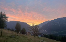 Hausansicht, © Manuel Leitmaier Blick auf ein Haus in einer Berglandschaft bei Sonnenuntergang.