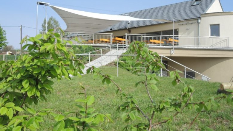 Heurigenlokal, © Familie Rohrhofer Heurigenlokal mit Terrasse und Sonnensegel, umgeben von grüner Landschaft.