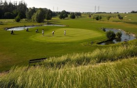Golfplatz Spillern, © Weinviertel Tourismus / Mandl Golfer auf einem grünen Golfplatz mit Teich und Bäumen im Hintergrund.