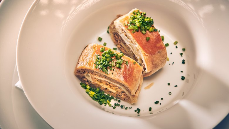 Traditioneller Fleischstrudel, © Niederösterreich Werbung/Andreas Hofer Zwei Stücke Fleischstrudel mit Schnittlauch auf weißem Teller serviert.