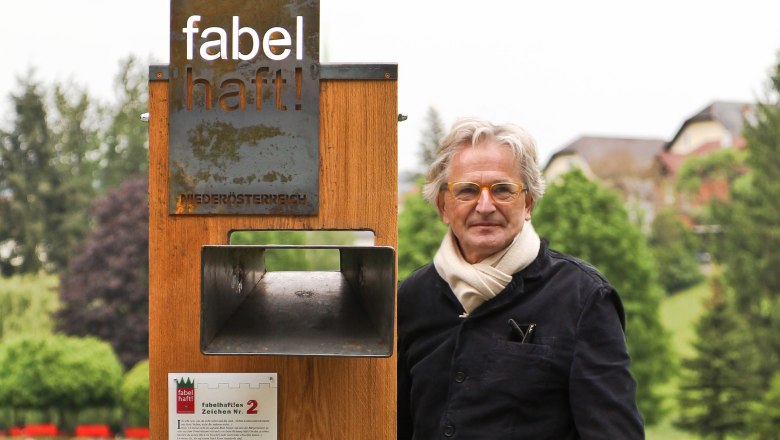 Fabelhafte Zeichen in der Buckligen Welt, © Nikolaus Pfusterschmid Ein Mann steht neben einem Holzschild mit der Aufschrift 'fabelhaft!' in einem Park.