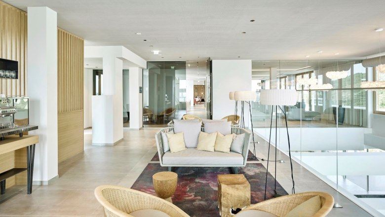 Steigenberger Krems, Bistro, © Steigenberger Hotel and Spa, Gregor Titze Moderner Aufenthaltsbereich im Hotel-Spa mit heller Einrichtung, Sofas, Stehlampen und einer Kaffeemaschine.