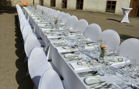 Tafeln im Weinviertel, © Weinviertel Tourismus GmbH Lange Tafel im Freien mit weißer Tischdecke und Gedecken vor einem historischen Gebäude.