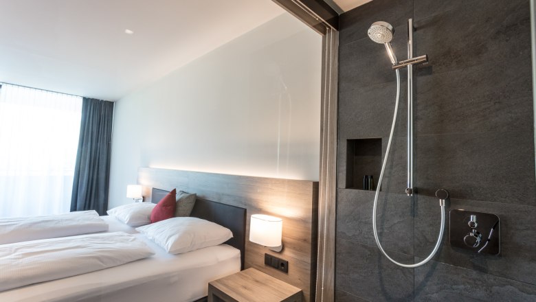 Doppelbett im modernen Doppelzimmer, © KASTNER NEW MEDIA - kastner.tv Modernes Hotelzimmer mit Doppelbett und offener Dusche.
