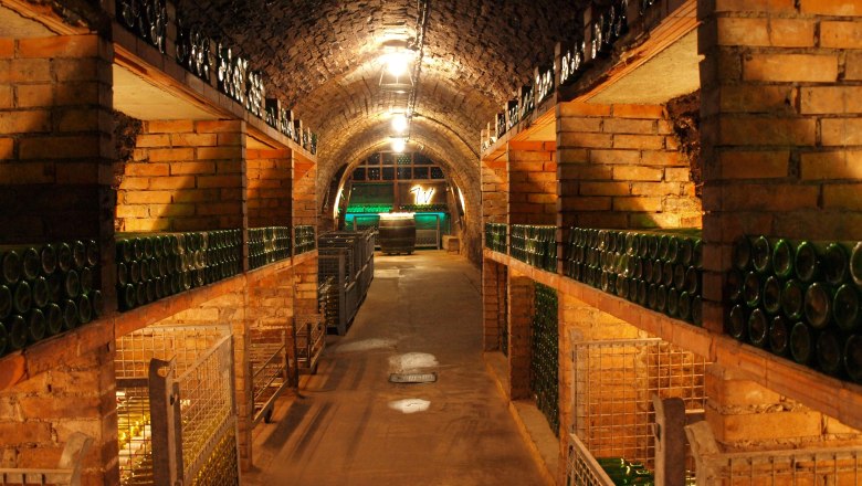 Weinkeller, © Weidenauer Ein Weinkeller mit Backsteinwänden und gestapelten Weinflaschen.