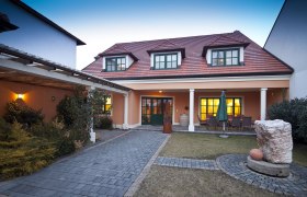 Gästehaus Berger, © Weingut und Gästehaus Berger Gästehaus mit rotem Dach und Garten im Vordergrund.