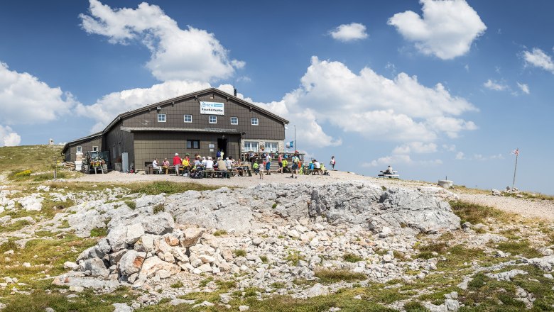 Fischerhütte auf 2049m, © WA/Franz Zwickl Fischerhütte auf dem Schneeberg mit Wanderern und blauem Himmel.
