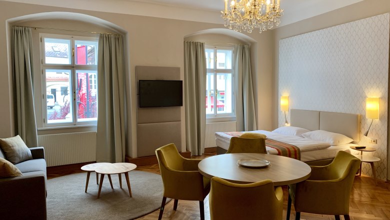 Residenz 2, © Daniela Matejschek Elegantes Zimmer mit Bett, Sofa, Tisch und Kronleuchter.