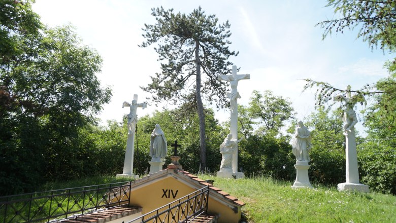 Kalvarienberg "Heiliger Berg", © Marktgemeinde Staatz Kreuzwegstation mit mehreren weißen Statuen und einem Kreuz im Freien.