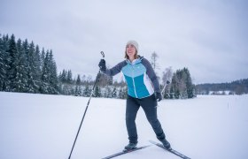 Langlaufen in der AktivWelt Freiwald, © Waldviertel Tourismus, Robert Herbst Eine Frau beim Langlaufen auf einer verschneiten Landschaft mit Bäumen im Hintergrund.