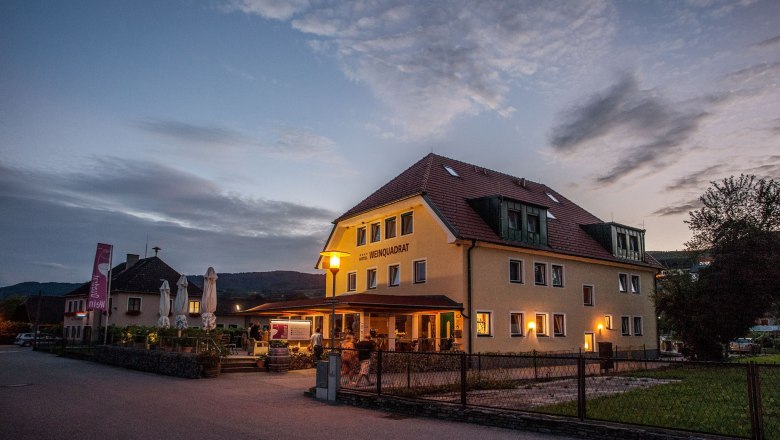 Ansicht Hotel Weinquadrat, © Martin Klotz Außenansicht des Hotels Weinquadrat bei Dämmerung mit beleuchteter Terrasse.