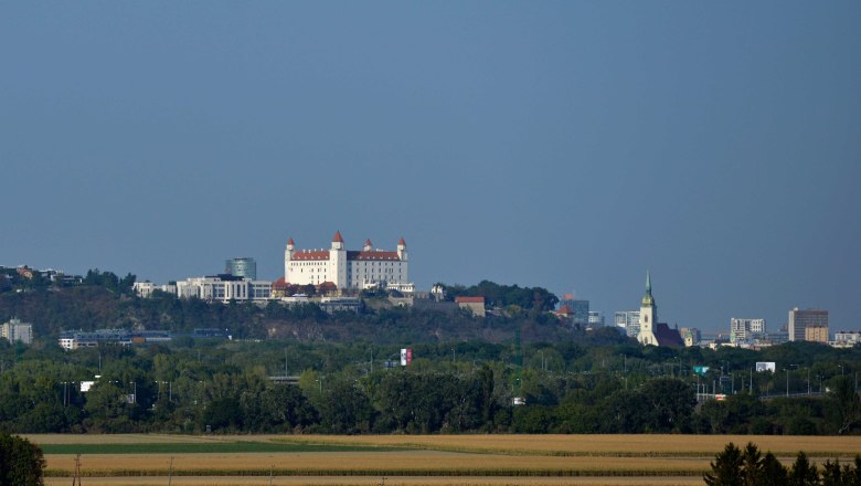 Bratislavablick, VIA.CARNUNTUM., © Donau Niederösterreich, Steve Haider Blick auf die Burg Bratislava und die Stadt im Hintergrund, umgeben von grüner Landschaft.