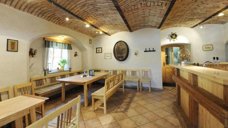 Heurigenlokal, © Steve Haider Innenansicht eines traditionellen Heurigenlokals mit Holzmöbeln und Ziegelgewölbe.