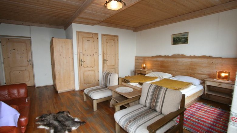 Komfort Doppelzimmer, © Scharfgger´s Raxalpen Resort Gemütliches Doppelzimmer mit Holzmöbeln, Doppelbett, Sesseln und Teppich.