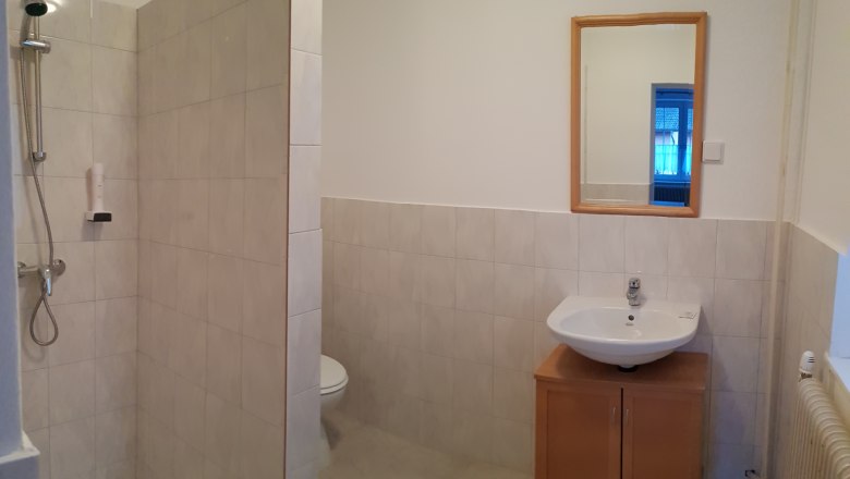 Bad, © mittendrin Dorfpension zum Ehn Badezimmer mit Dusche, Waschbecken und Spiegel.