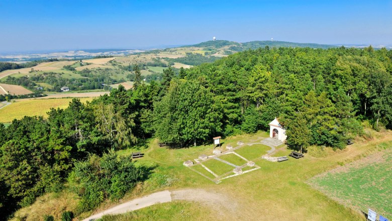 Blick vom Aussichtsturm auf einen Gebäudegrundriss, © Leiser Berge Landschaftsansicht von einem Aussichtsturm mit Wäldern, Feldern und einer kleinen Kapelle.