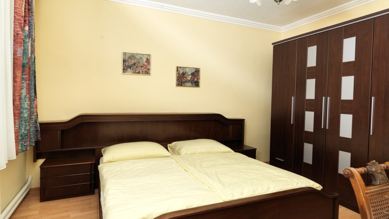 Komfortzimmer, © Gasthof "Der Zesch" Ein gemütliches Schlafzimmer mit einem Doppelbett, einem großen Kleiderschrank und zwei Bildern an der Wand.