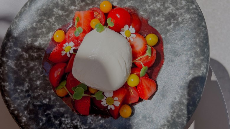 Kulinarische Köstlichkeiten, © Pebbles Ein Teller mit Burrata, Erdbeeren, Tomaten und essbaren Blüten.