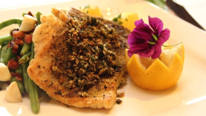 Waldschenke Schreiber, © Waldschenke Schreiber Ein Teller mit gebratenem Fischfilet, dekoriert mit einer Blume und einer Zitronenscheibe, serviert mit grünen Bohnen und Speck.