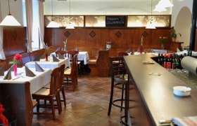 Innenansicht vom Melker Stadtheurige, © Koloman - Der Melker Stadtheurige Innenansicht eines gemütlichen Restaurants mit Holzmöbeln und gedeckten Tischen.