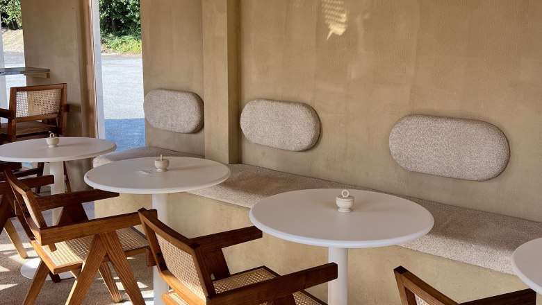 Gemütlicher Innenbereich, © Pebbles Innenbereich eines Cafés mit Holzmöbeln und runden Tischen.