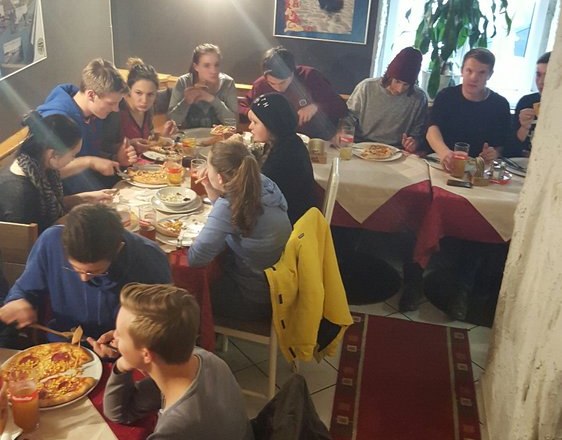 Pizzeria Borsalino, © Pizzeria Borsalino Gruppe von Menschen isst Pizza in einem gemütlichen Restaurant mit Höhlenwänden.