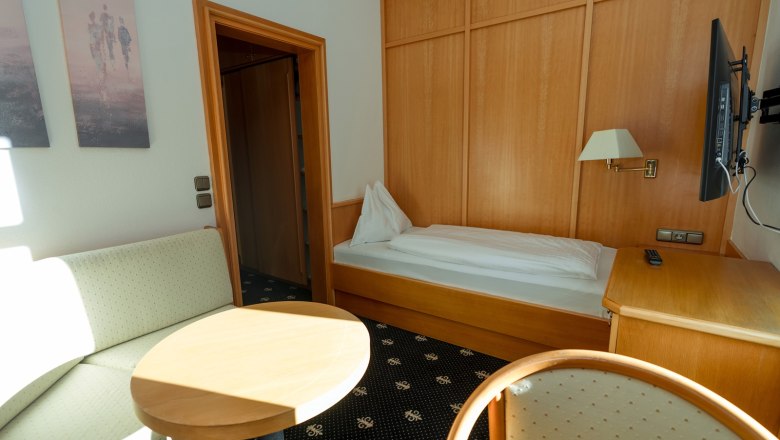 Einzelzimmer, © Sporthotel Semmering Einzelzimmer mit Bett, Sofa, Tisch und Fernseher.