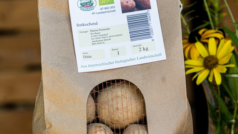 Erdäpfel, © Martina Siebenhandl Ein Papiersack mit Bio Erdäpfeln, daneben gelbe Blumen.