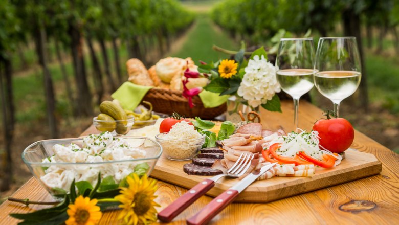 TDR-Heurigenjause, © Verena-Saloukeh Heurigenjause auf einem Holztisch im Weinberg.