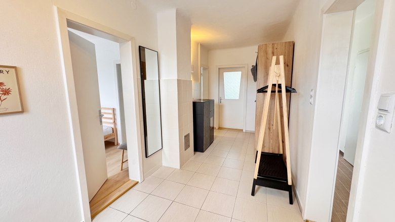 Lesezimmer Flur, © Christoph Menhofer Heller Flur mit Fliesenboden, Spiegel, Garderobe und Türen zu angrenzenden Räumen.