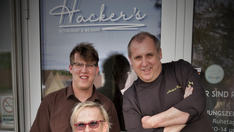 Norbert Hacker und sein Team, © Restaurant Hacker's Drei Personen vor dem Eingang von Hacker's Restaurant & Weinbar.