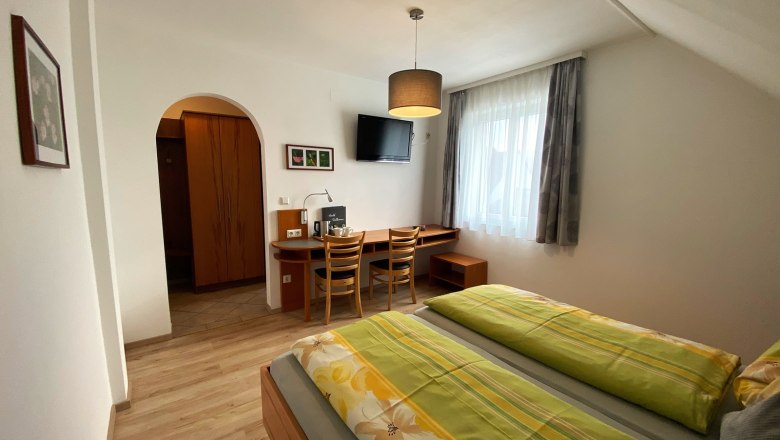 Doppelzimmer, © Trachsler Ein gemütliches Doppelzimmer mit zwei Betten, Schreibtisch, Stühlen und einem Fernseher an der Wand.