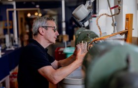 KRISTALLIUM glas.erleben., © Waldviertel Tourismus, Matthias Streibel Ein Mann bearbeitet ein Glas an einer Schleifmaschine in einer Werkstatt.