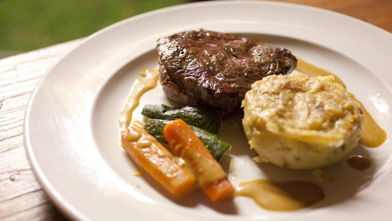 Gutes Essen in der Bierinsel, © Weinviertel Tourismus GmbH / Wurnig Ein Teller mit einem Stück Fleisch, Gemüse und einem Kartoffelgratin.