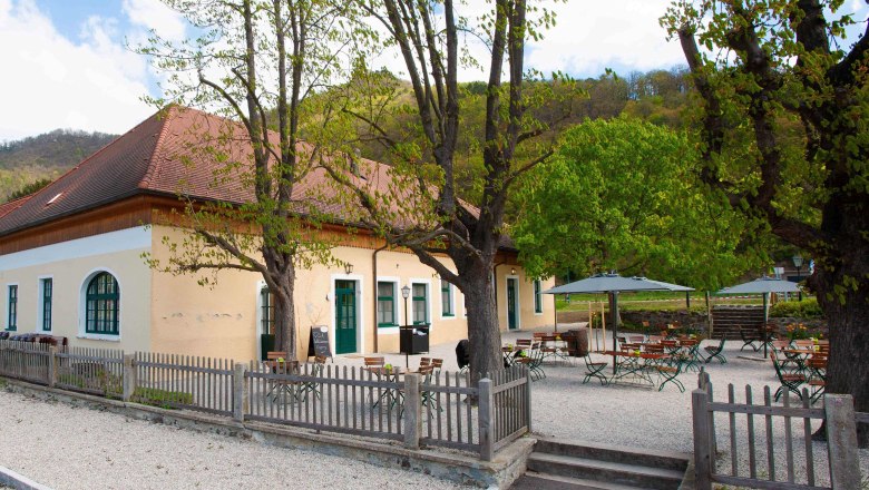 Aggsteinerhof Aussenansicht, © Daniels Außenansicht eines gelben Gebäudes mit rotem Dach und Biergarten.