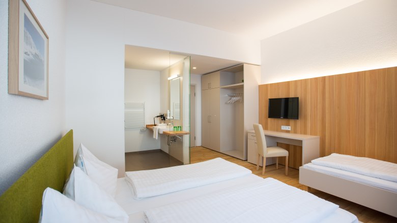 JoSchi Sporthaus Hochkar, © JoSchi Sporthaus Hochkar Modern eingerichtetes Hotelzimmer mit zwei Betten, Schreibtisch, Fernseher und offenem Badezimmer.