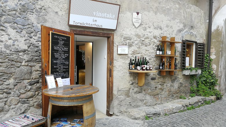 vinotake im Torwächterhaus, © Roman Zöchlinger Eingang zu einem Weinladen in einem alten Steingebäude mit Weinfässern und Weinflaschen an der Wand.